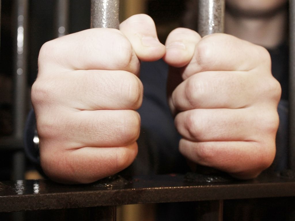 person holding bars in jail