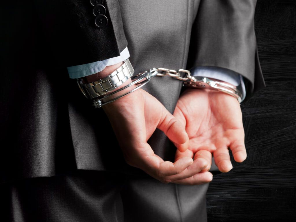 hands of a white collar worker in handcuffs
